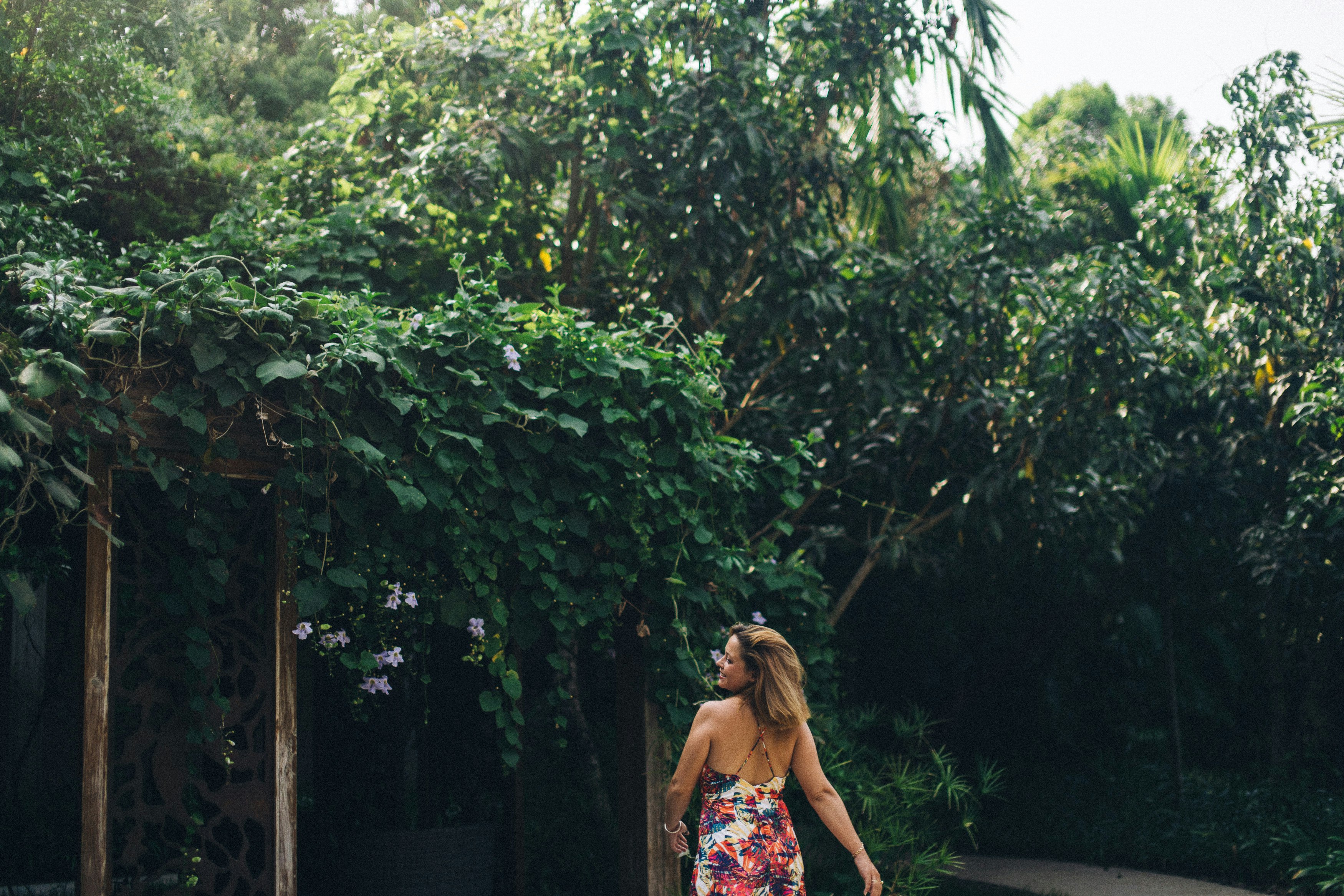 woman in blue and red floral dress standing near green trees during daytime